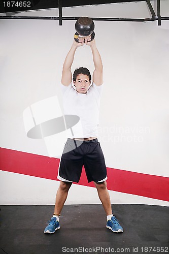 Image of Young man doing kettlebell workout on gym