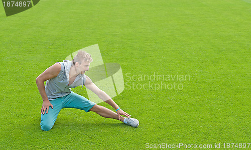 Image of Young man exercising on sports field