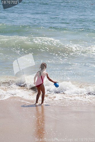 Image of Little Girl Playing with a Bucket on the Beach