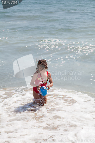 Image of Little Girl Playing with a Bucket on the Beach