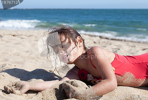 Image of Little Girl Relaxing on the Beach Covered in Sand