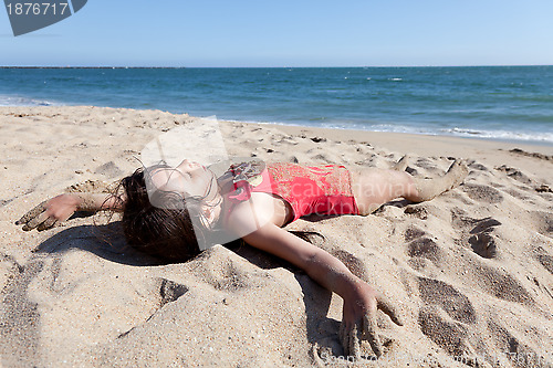 Image of Little Girl Relaxing on the Beach Covered in Sand