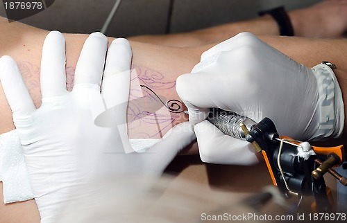 Image of Tattoo artist makes the tattoo on arm