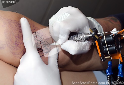 Image of Tattoo artist makes the tattoo on arm