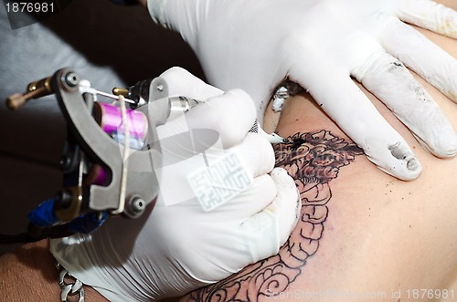 Image of Tattoo artist makes the tattoo on arm