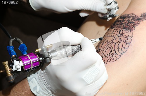 Image of Tattoo artist makes the tattoo on arm