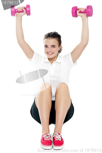 Image of Young girl sitting on floor and doing fitness exercise