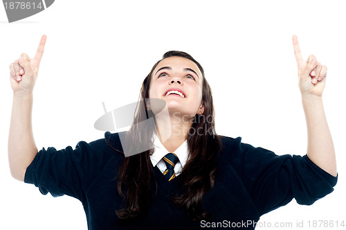 Image of Excited young teenage girl looking and pointing upwards