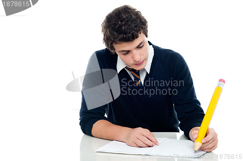 Image of Young schoolboy taking up his test at school