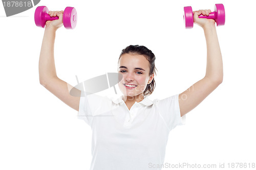 Image of Smiling girl working out. Dumbbells above her head