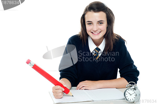 Image of Profile shot of smiling school girl taking down notes