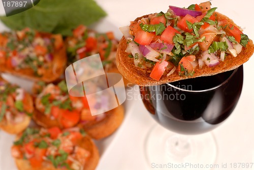 Image of Bruschetta resting on a glass of wine with additional bruschetta