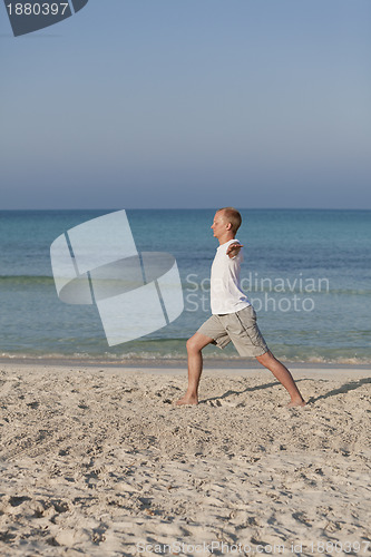 Image of Man makes yoga sports on the beach portrait