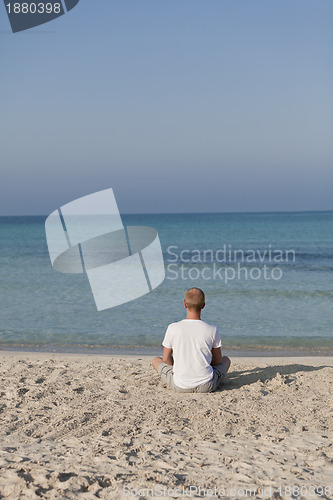 Image of Man makes yoga sports on the beach portrait