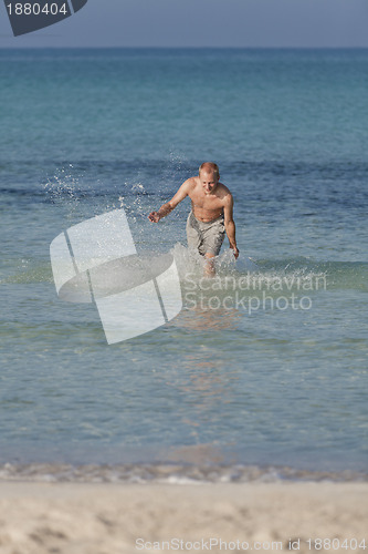 Image of man running on the beach in water portrait