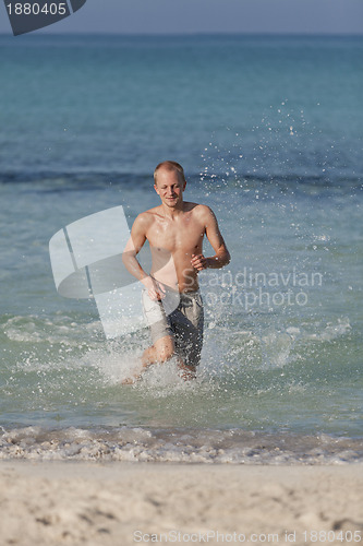 Image of man running on the beach in water portrait