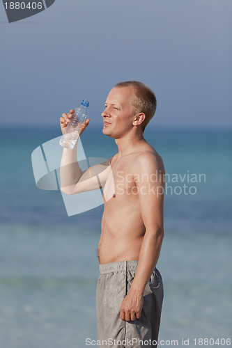 Image of Man drinking water from a bottle on the beach portrait