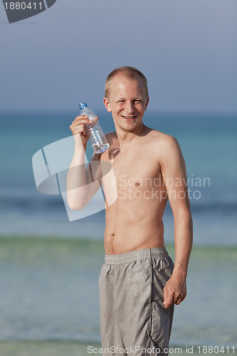 Image of Man drinking water from a bottle on the beach portrait