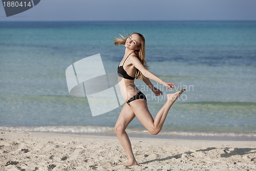 Image of Woman with bikini jumping happily on the beach landscape