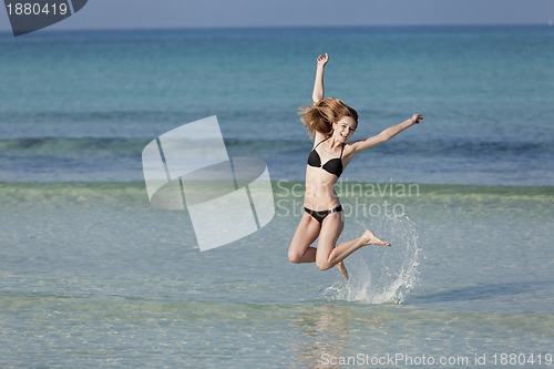 Image of Woman with bikini jumping in the sea landscape