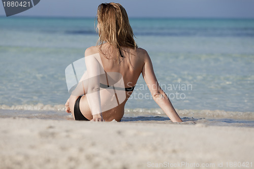 Image of Young woman in black bikini on the beach in the water landscape