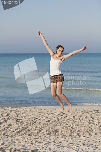 Image of Cheerful woman jumping laughing at beach portrait