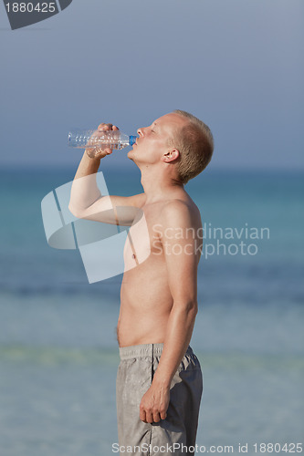 Image of Man drinking water from a bottle on the beach portrait