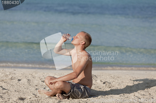 Image of Man drinking water from a bottle on the beach landscape