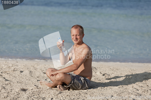 Image of Man drinking water from a bottle on the beach landscape