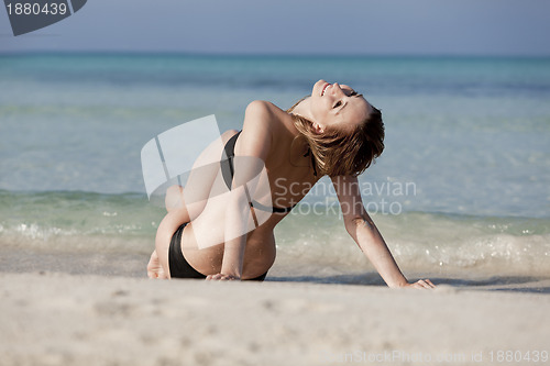 Image of Young woman in black bikini on the beach in the water landscape