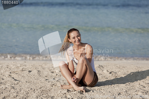 Image of Woman drinking water from a bottle on the beach landscape