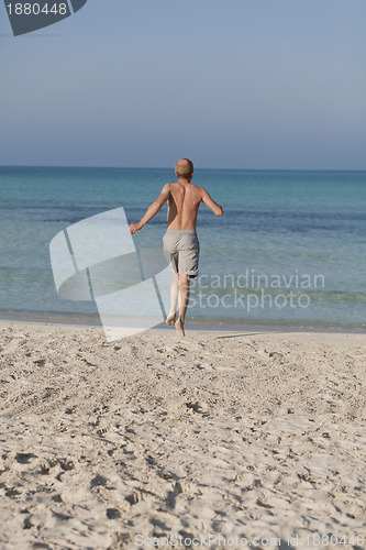 Image of man running on the beach in water portrait