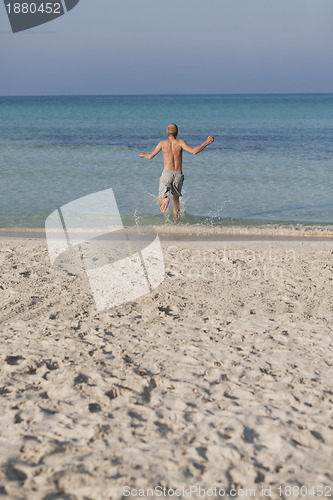 Image of man running on the beach in water portrait