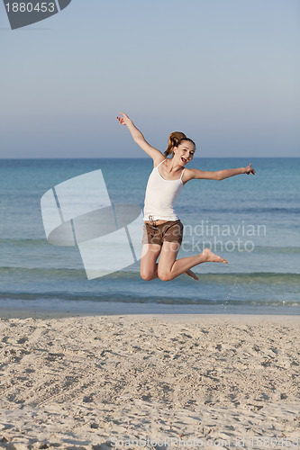 Image of Cheerful woman jumping laughing at beach portrait