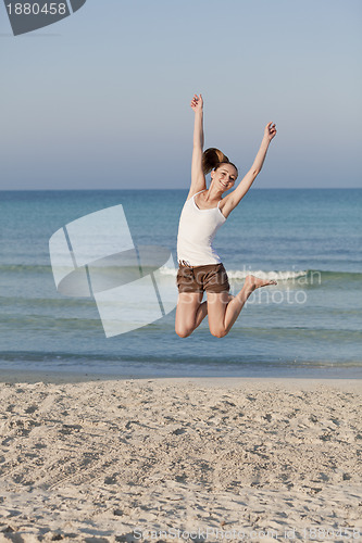 Image of Cheerful woman jumping laughing at beach portrait