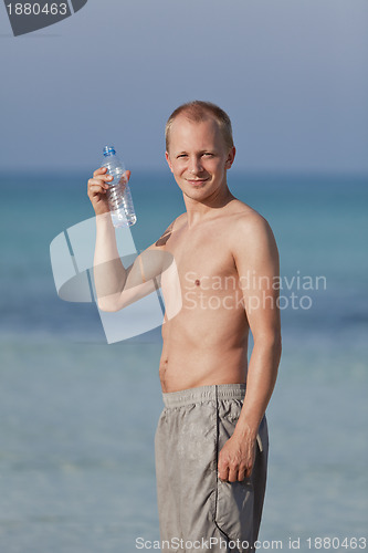 Image of Man drinking water from a bottle on the beach portrait