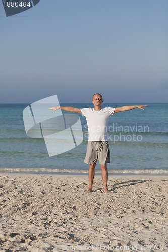 Image of Man makes yoga sports on the beach portrait
