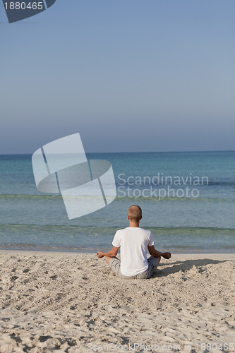 Image of Man makes yoga sports on the beach portrait