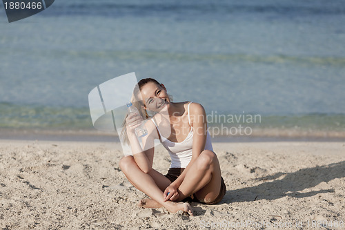 Image of Woman drinking water from a bottle on the beach landscape