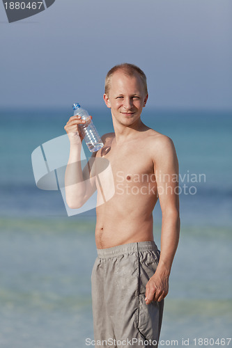 Image of Man drinking water from a bottle on the beach portrait