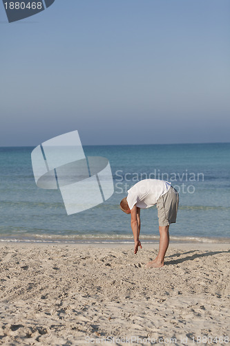 Image of Man makes yoga sports on the beach portrait
