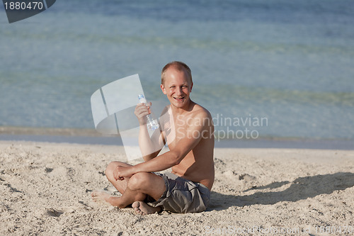 Image of Man drinking water from a bottle on the beach landscape