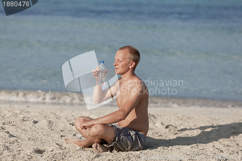 Image of Man drinking water from a bottle on the beach landscape