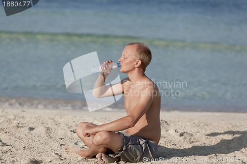 Image of Man drinking water from a bottle on the beach landscape