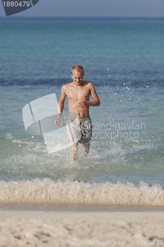 Image of man running on the beach in water portrait