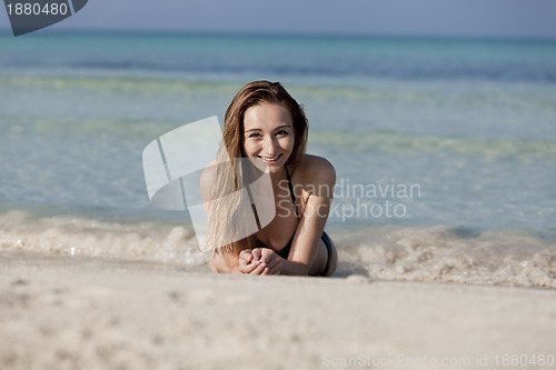 Image of Young woman in black bikini on the beach in the water landscape