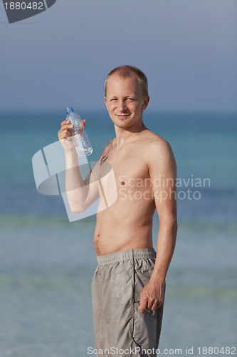 Image of Man drinking water from a bottle on the beach portrait