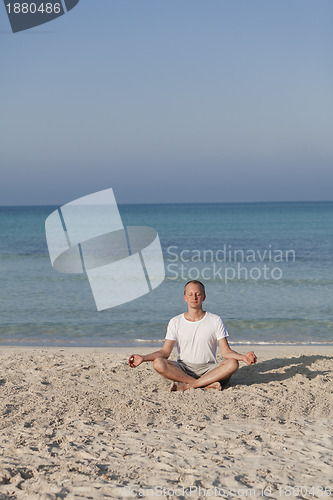 Image of Man makes yoga sports on the beach portrait