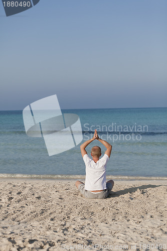 Image of Man makes yoga sports on the beach portrait