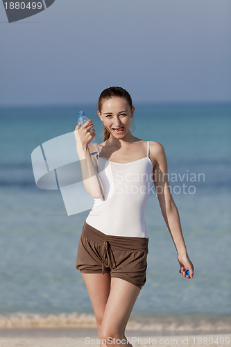 Image of Woman drinking water from a bottle on the beach portrait